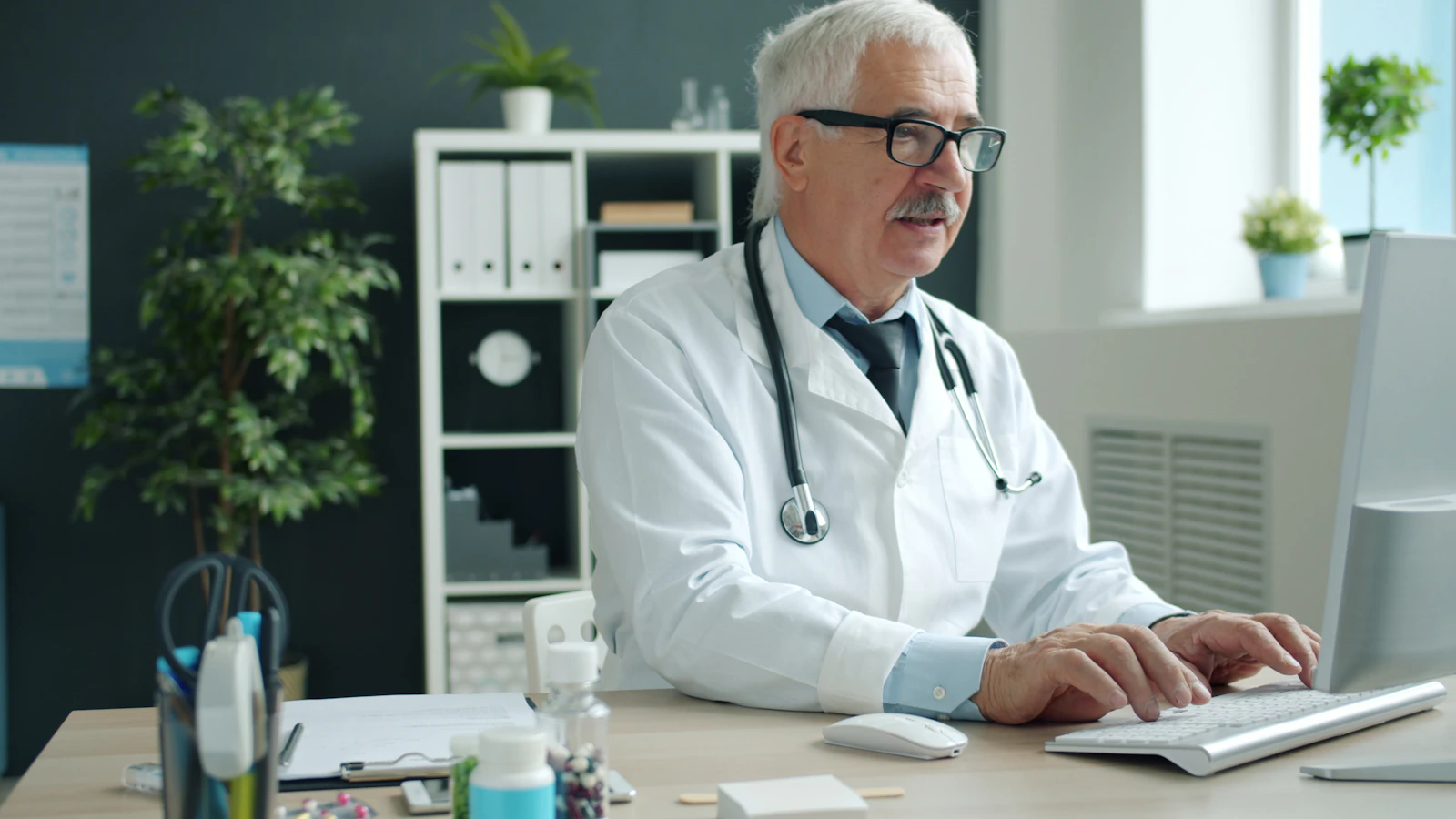 Physician reviewing patient records at a desktop computer